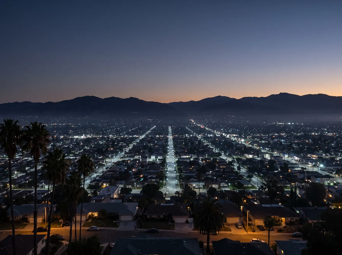 Illustration: the San Fernando Valley's street grid lit before dawn, seen from the hills, mountains on the horizon.